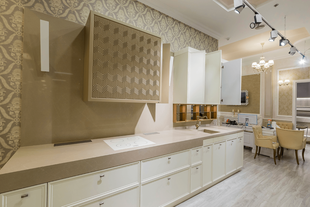 Moderne Küche mit heller Arbeitsplatte, Einbauschrank, Kochfeld und Oberschränken an einer gemusterten Wand.